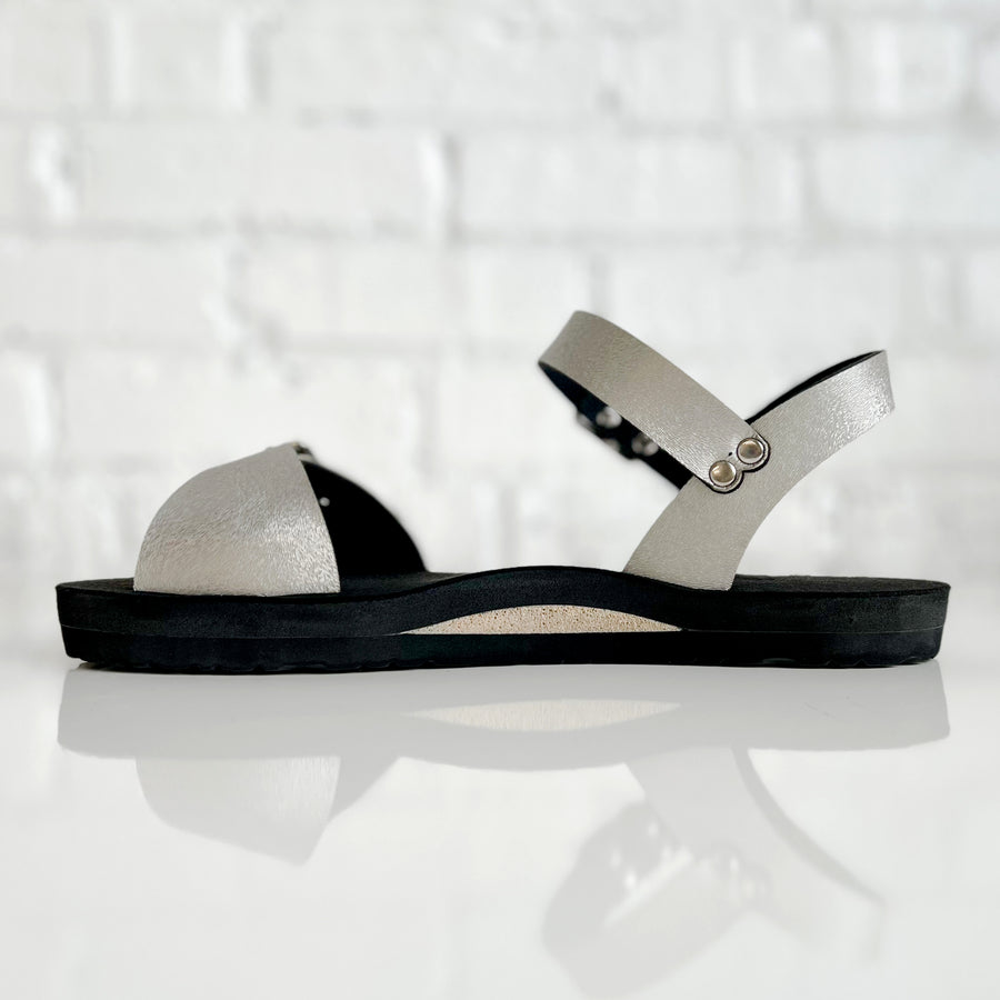 Side view of a flat, padded vegan sandal in champagne color, showing a neutral color padded arch support insert