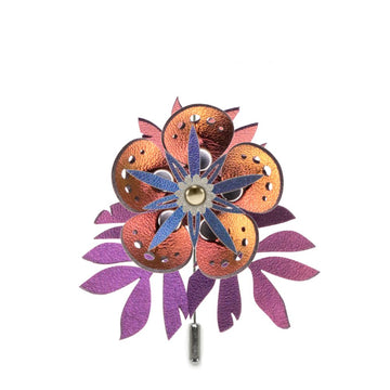 A stick pin featuring a red-bronze flower and intricately cut iridescent purple flowers shown on a white background
