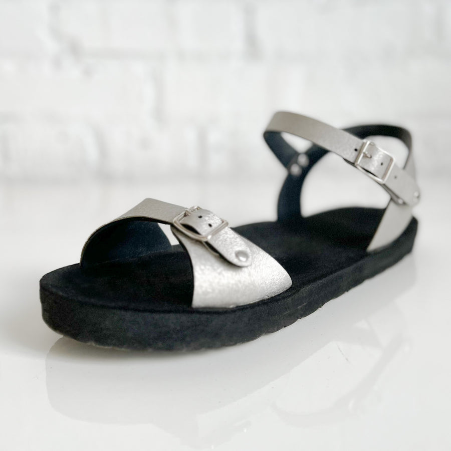 Angle view of a flat, padded vegan sandal in matte black with an ankle strap