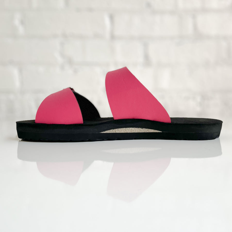 Side view of a flat, padded vegan sandal in hot pink, showing a neutral color padded arch support insert