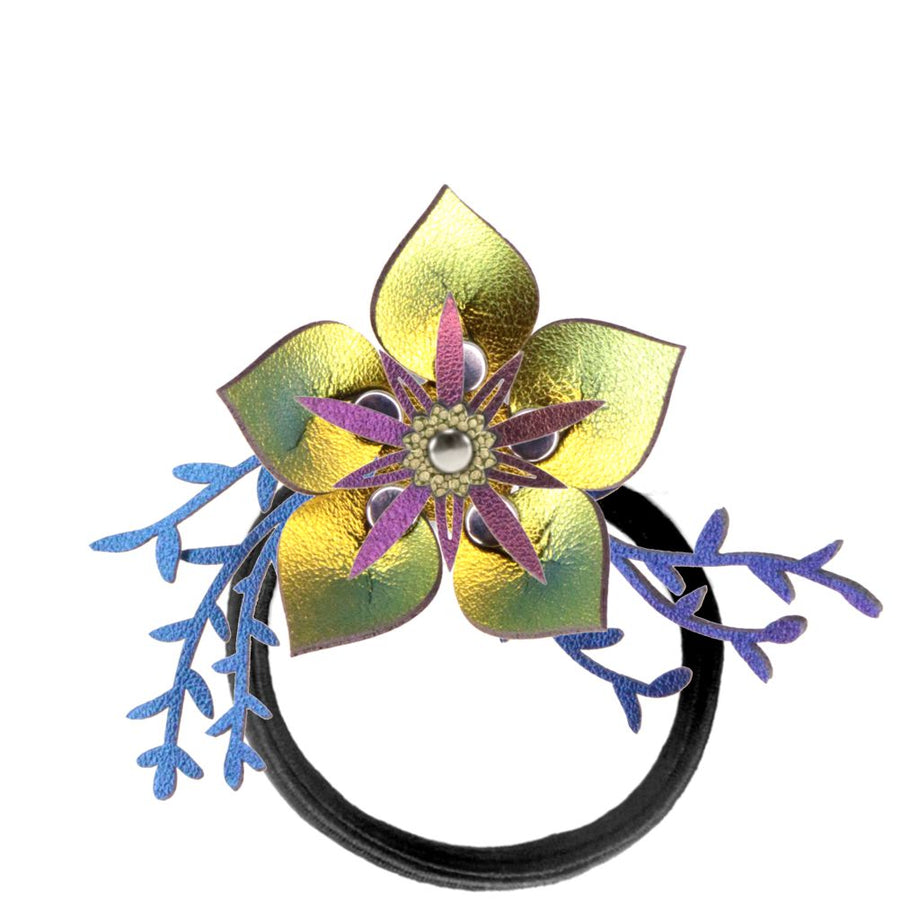 A thick elastic hair tie featuring a large iridescent gold faux leather flower accented by iridescent blue leaves shown on a white background