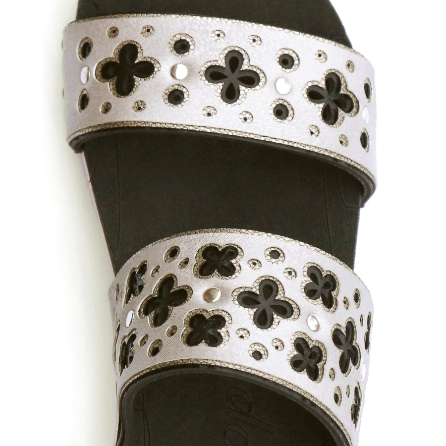 Detail view of a sandal with laser cut layers in black and metallics