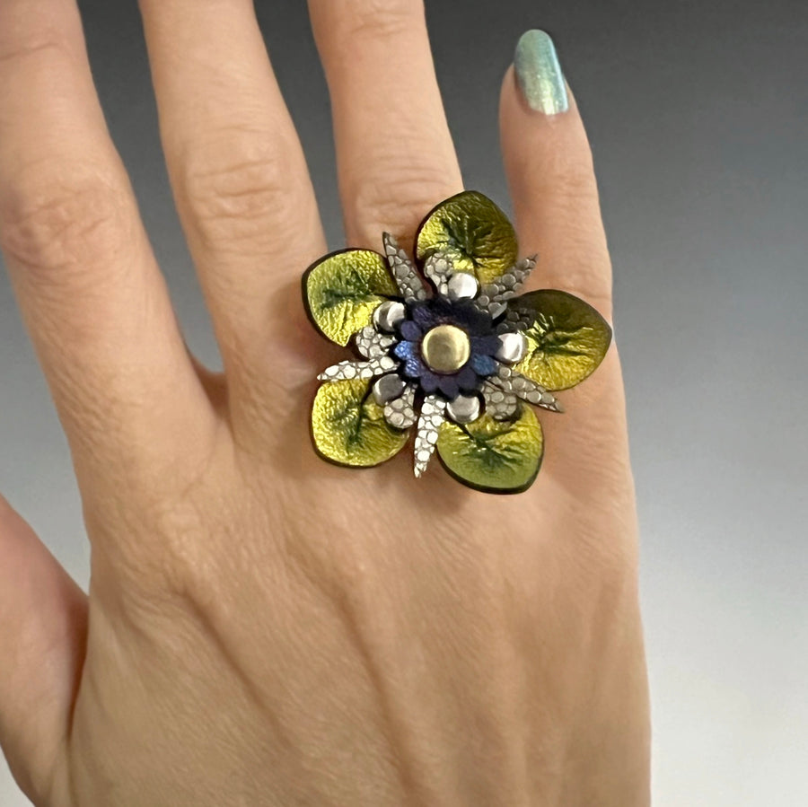 A faux leather ring with a gold iridescent flower and gold stamen on a model's hand