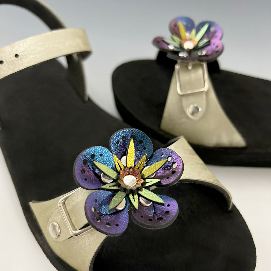 Shoe clips with blue iridescent faux leather flowers shown on a pair of gold sandals