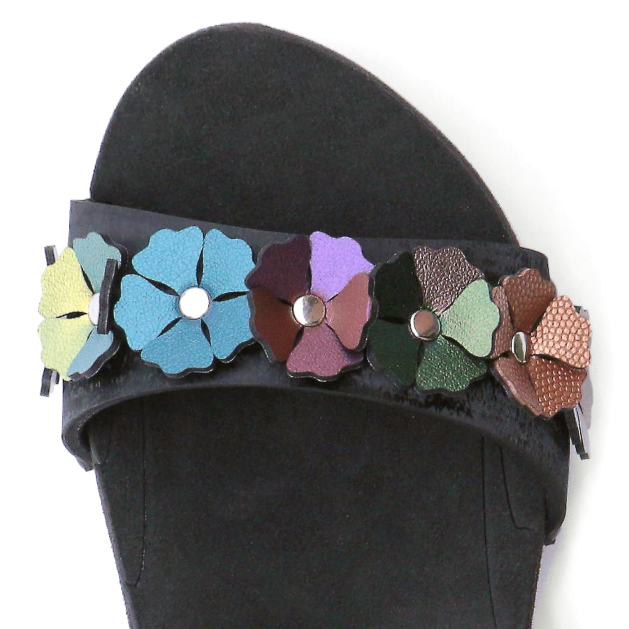 Detail view of a sandal with 7 flowers along the toe, shown with a black ankle strap