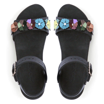 Top view of a sandal with 7 flowers along the toe, shown with a black ankle strap