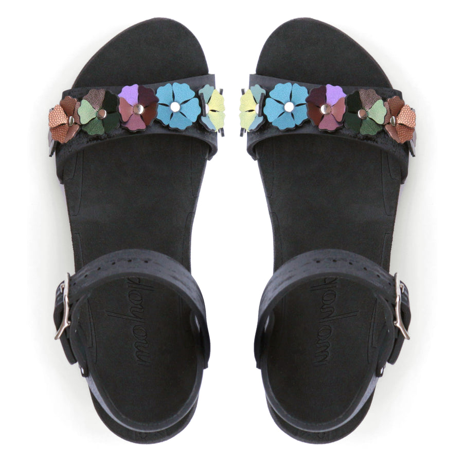 Top view of a sandal with 7 flowers along the toe, shown with a black ankle strap