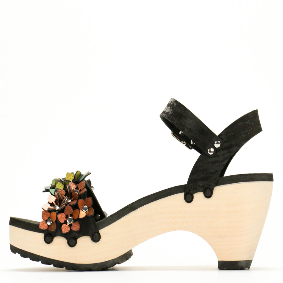 Instep view of a sandal with a rainbow of glittery flowers on teh toes and an adjustable black ankle strap