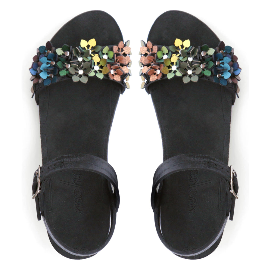 Top view of a sandal with a rainbow of glittery flowers on teh toes and an adjustable black ankle strap