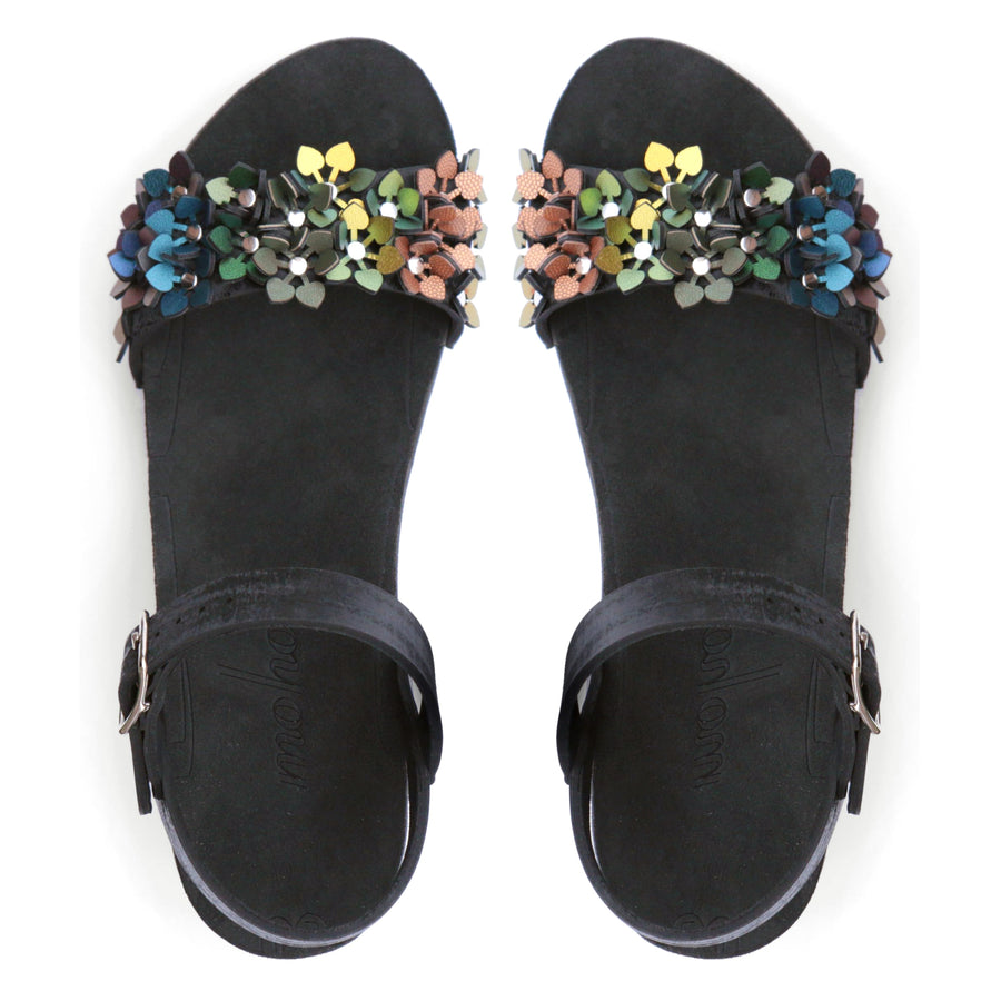 Top view of a sandal with a rainbow of glittery flowers on teh toes and an adjustable black ankle strap