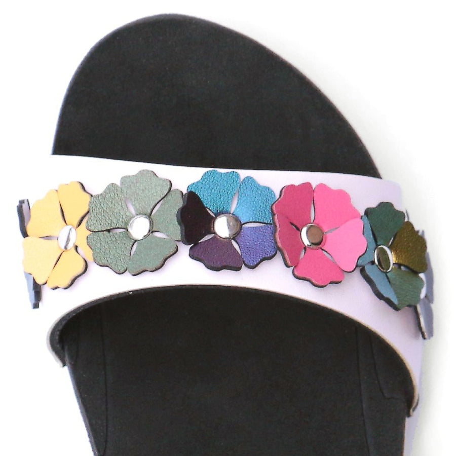 Detail view of a sandal with7 simple colorful flowers and a hot pink ankle strap
