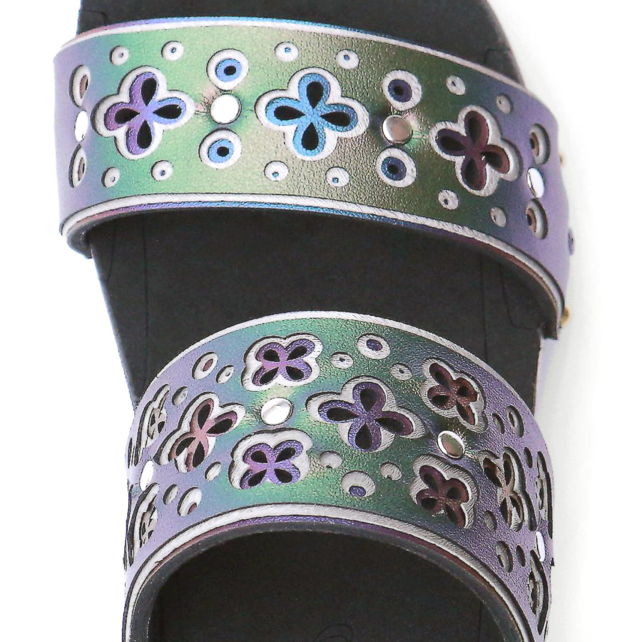 Detail view of a sandal with layers of laser cut material in greens and blues