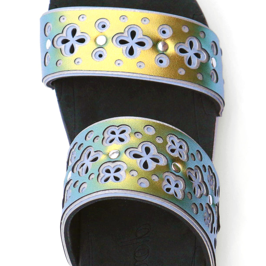 Detail view of a sandal with laser cut uppers in light blue, silver, and scarab