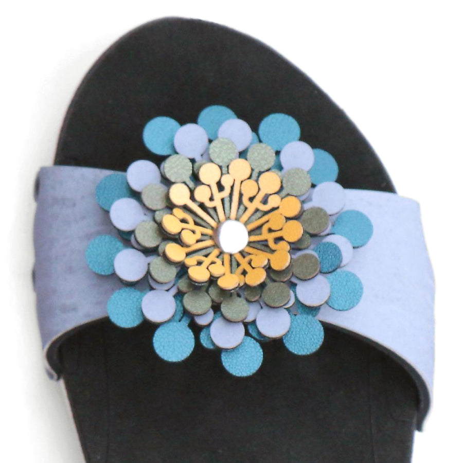 Detail view of a sandal in arctic with an abstract floral pompom at the toe