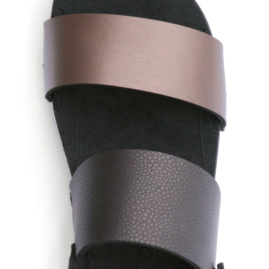 Detail view of sandals with a deep tan front strap and brown back strap
