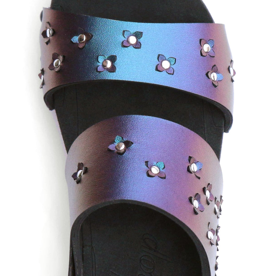 Detail view of sandals in iridescent blue with tiny laser cut flowers sprinkled on the upper