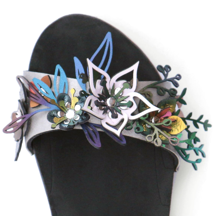 Detail view of sandals with a a 3D laser cut floral motif in a rainbow of colors
