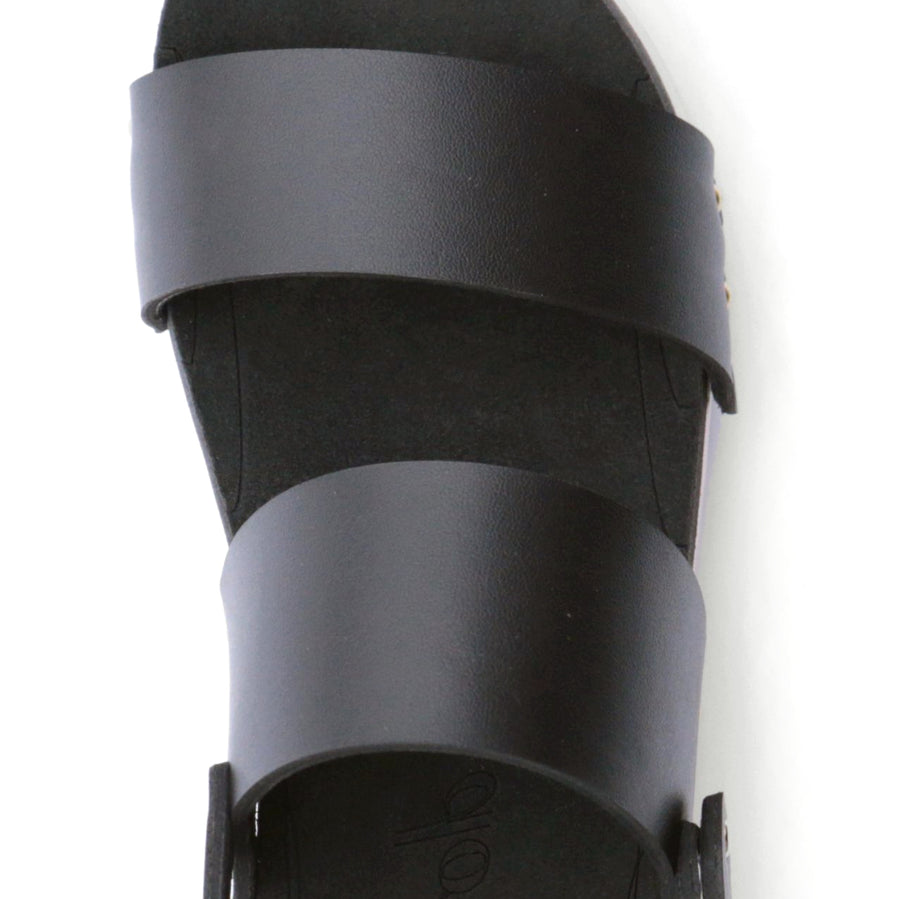 Detail view of a sandal with wide chunky straps in matte black