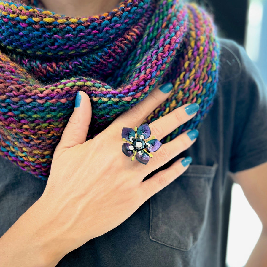 An adjustable ring featuring a 3D laser cut flower in shades of teal, purple , silver and gold
