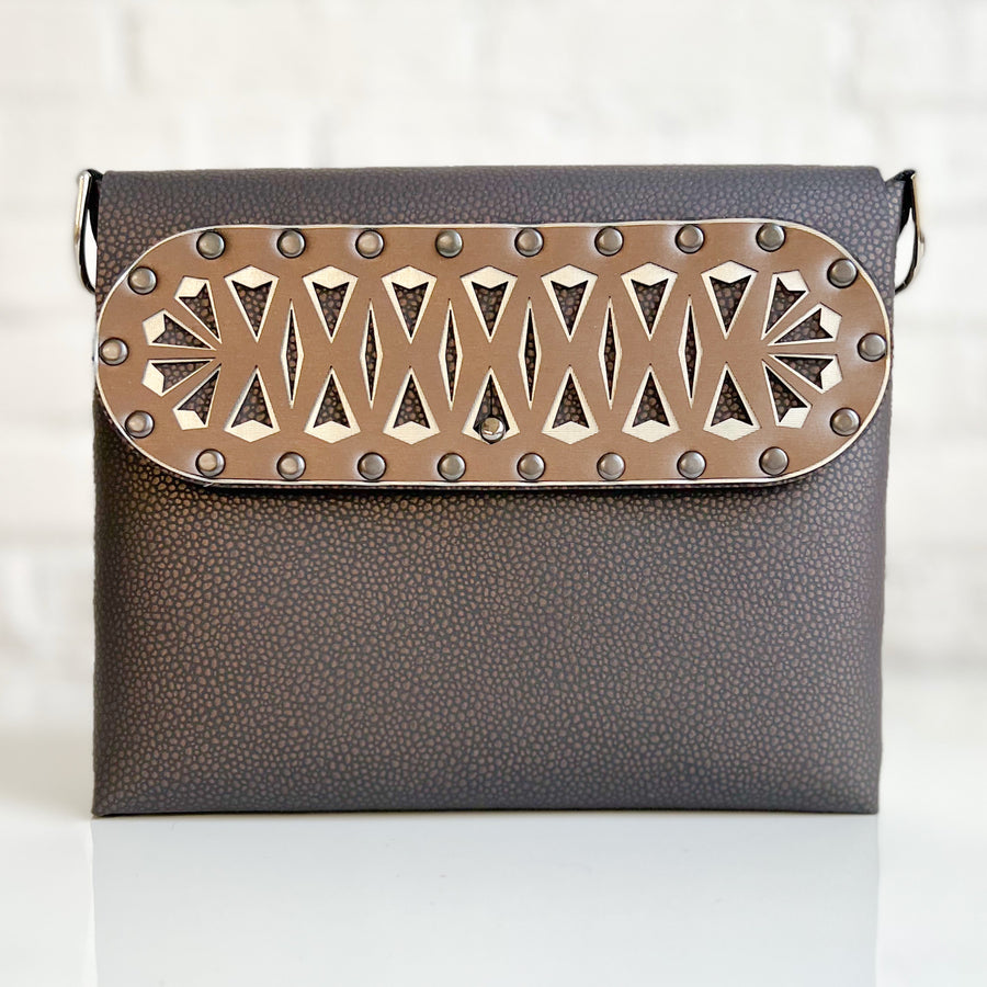 A square crossbody bag in brown vegan faux leather with a laser cut front