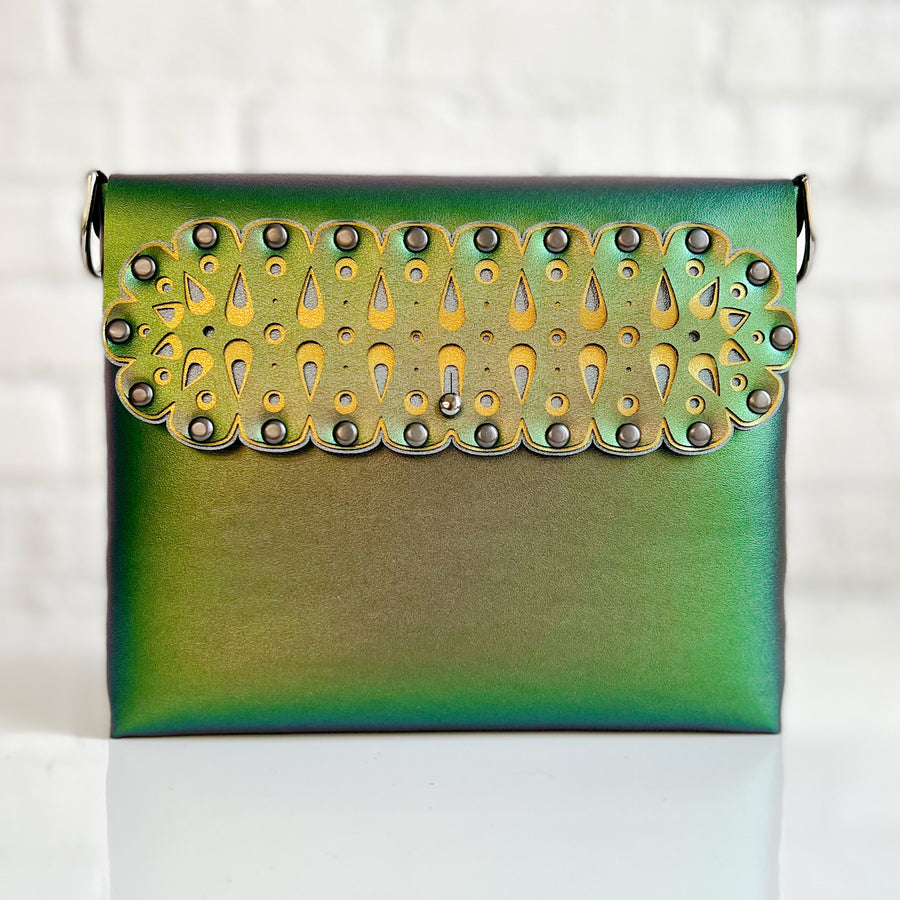 A square crossbody bag in iridescent green vegan faux leather with a laser cut front