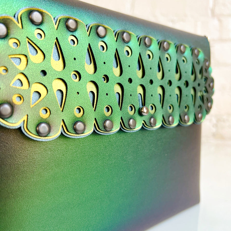 Closeup shot of a square crossbody bag in iridescent green vegan faux leather with a laser cut front