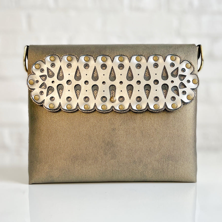 A square crossbody bag in metallic gold vegan faux leather with a laser cut front