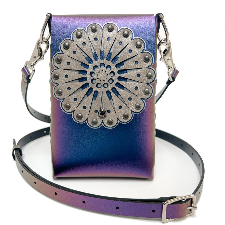 A small bag in blue iridescent vegan leather with a laser cut front flap and adjustable crossbody strap