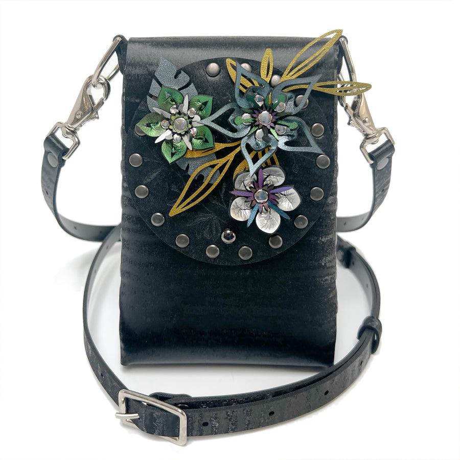 A small bag in black chinchilla vegan leather with a 3D floral laser cut front flap and adjustable crossbody strap