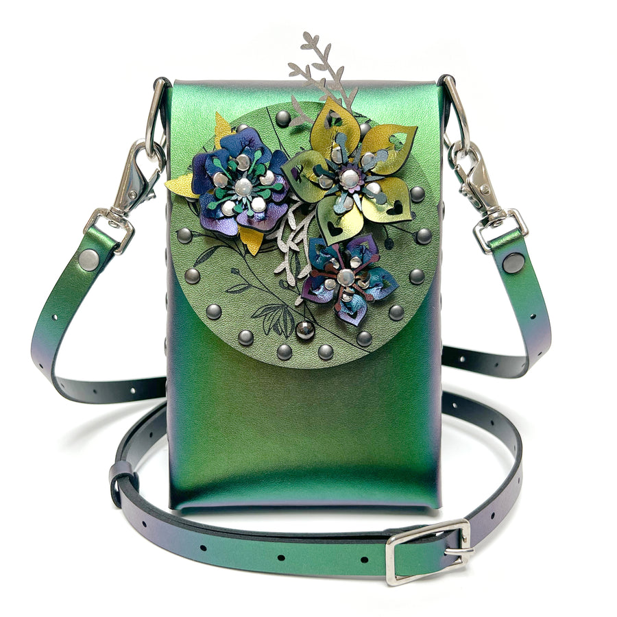A small bag in green iridescent vegan leather with a 3D floral laser cut front flap and adjustable crossbody strap