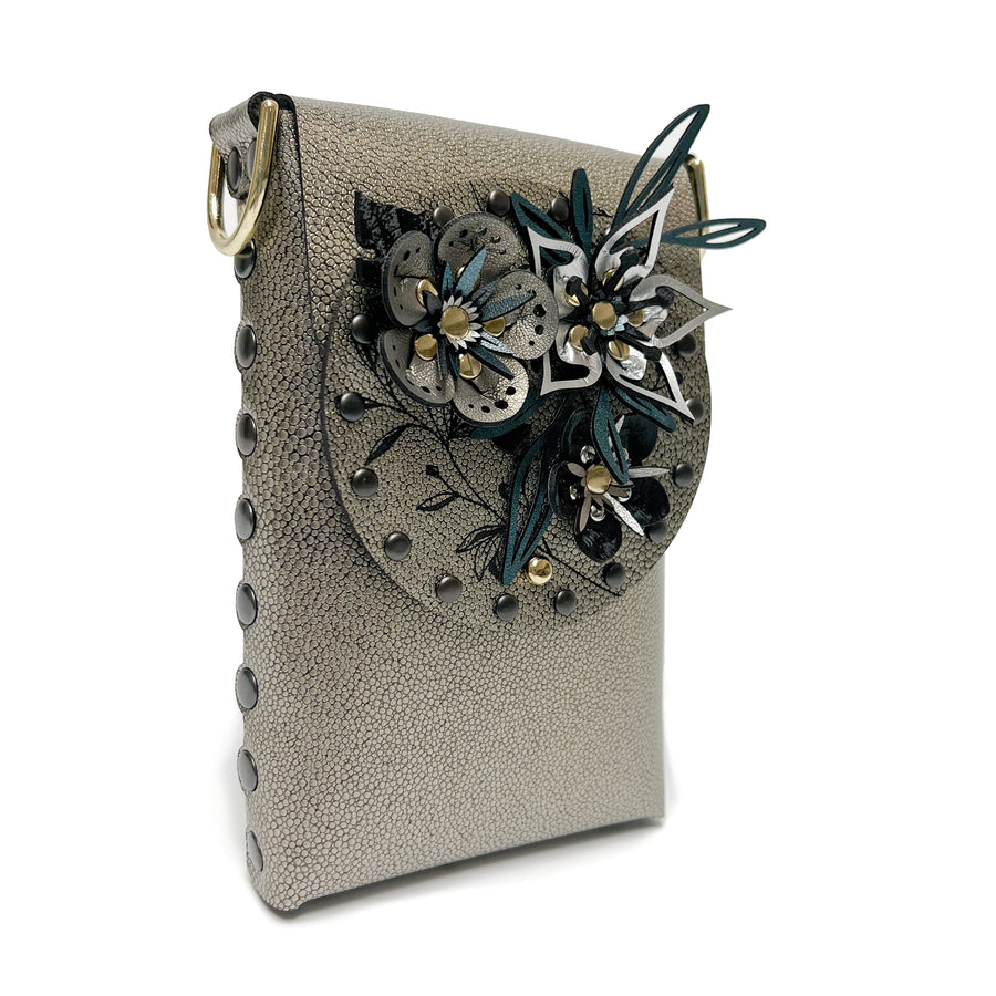 Side photo of a small bag in gold shagreen vegan leather with a 3D floral laser cut front flap and adjustable crossbody strap