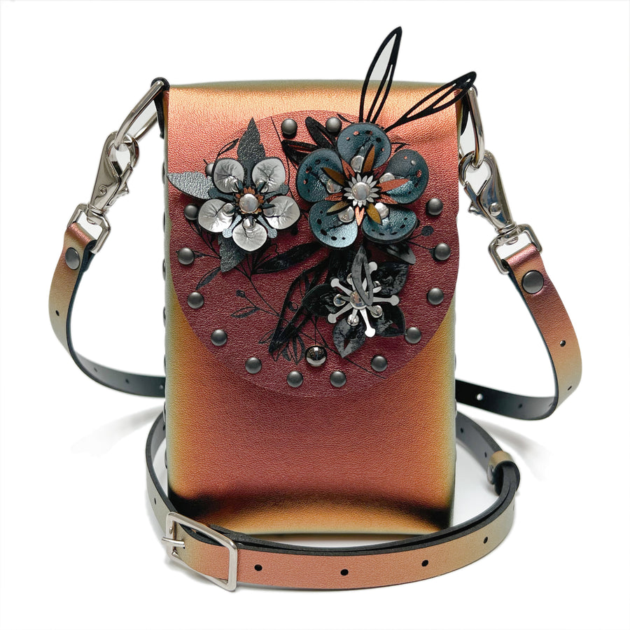 A small bag in red iridescent vegan leather with a 3D floral laser cut front flap and adjustable crossbody strap