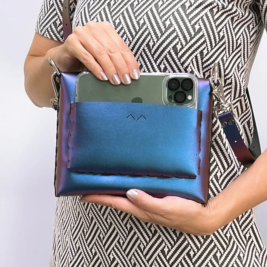 Woman placing Iphone Max into exterior  pocket of Peacock Square Flower Handbag. 