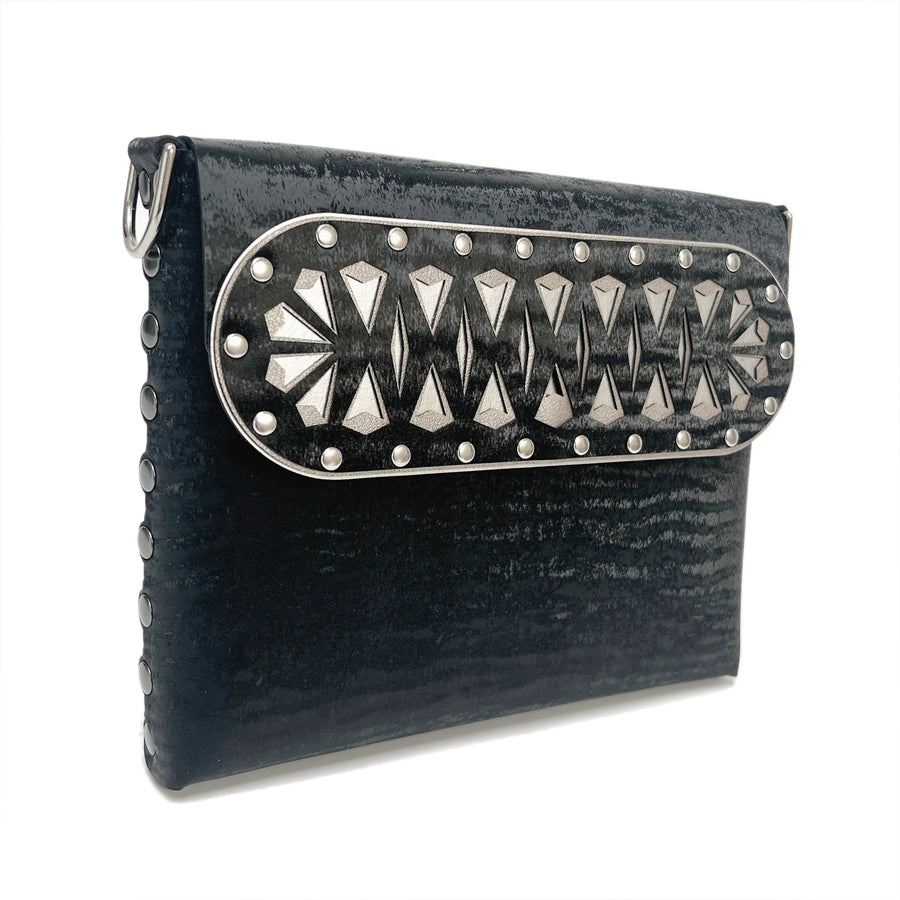 Front side angle view of the Black Chinchilla Arrow Bag's laser cut arrow motif styled flap. 