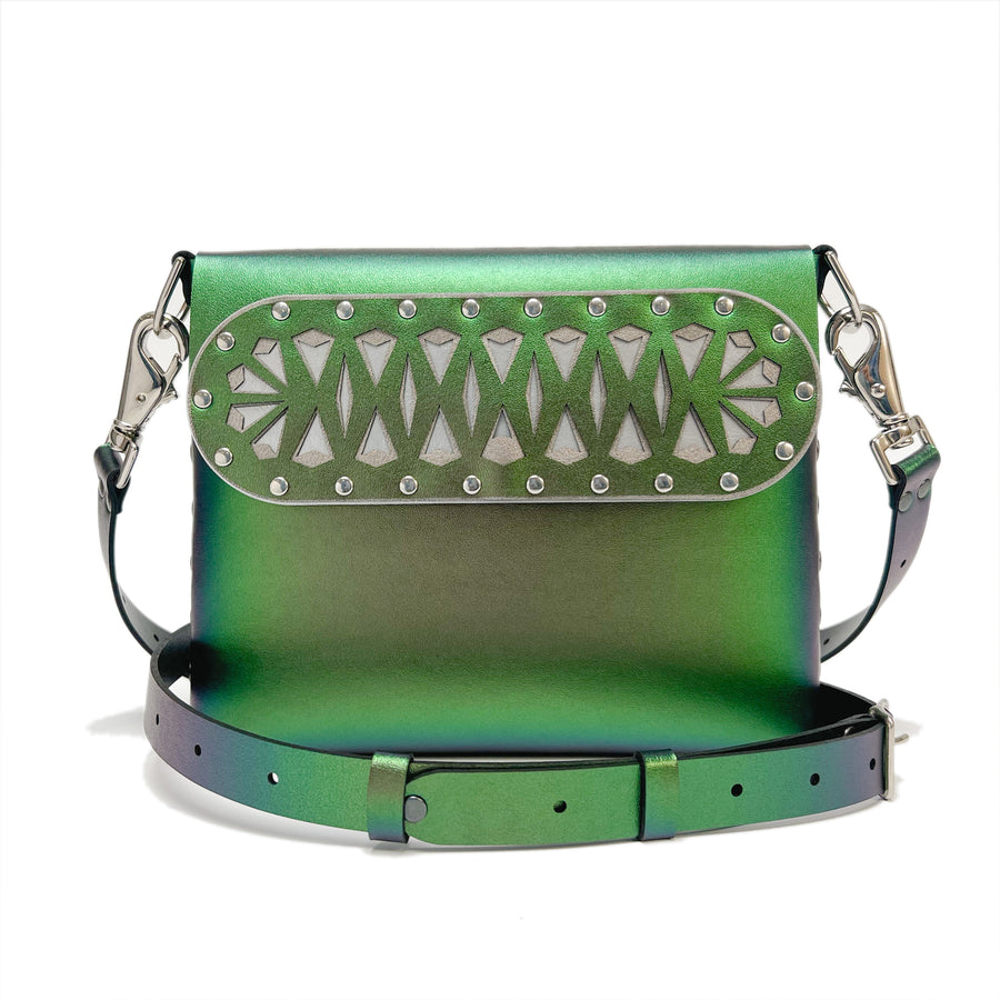 A front shot, including strap, of a square crossbody bag in iridescent green vegan faux leather with a laser cut front